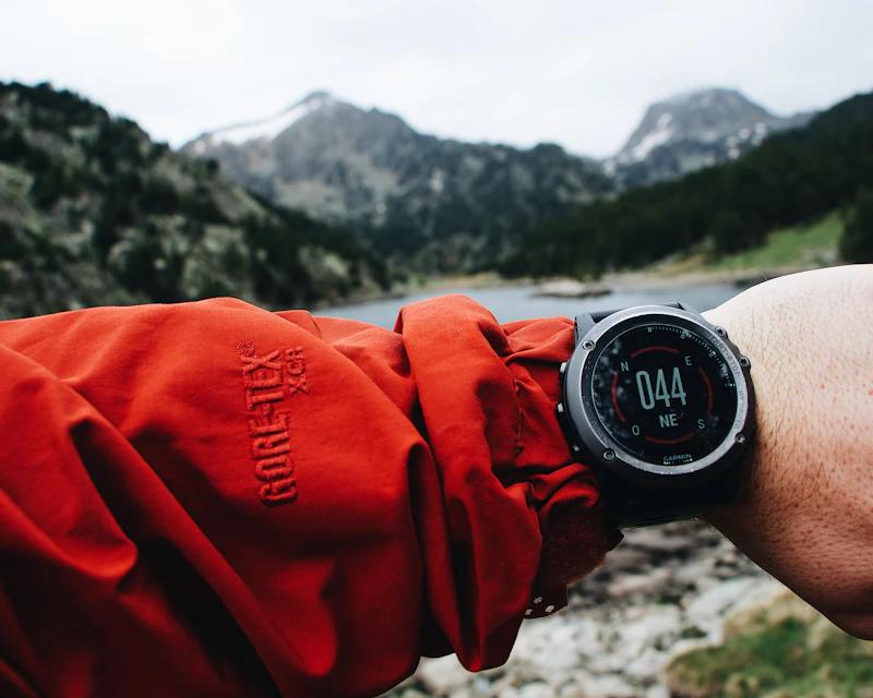 Outdoor-Smartwatch am Handgelenk vor Bergkulisse